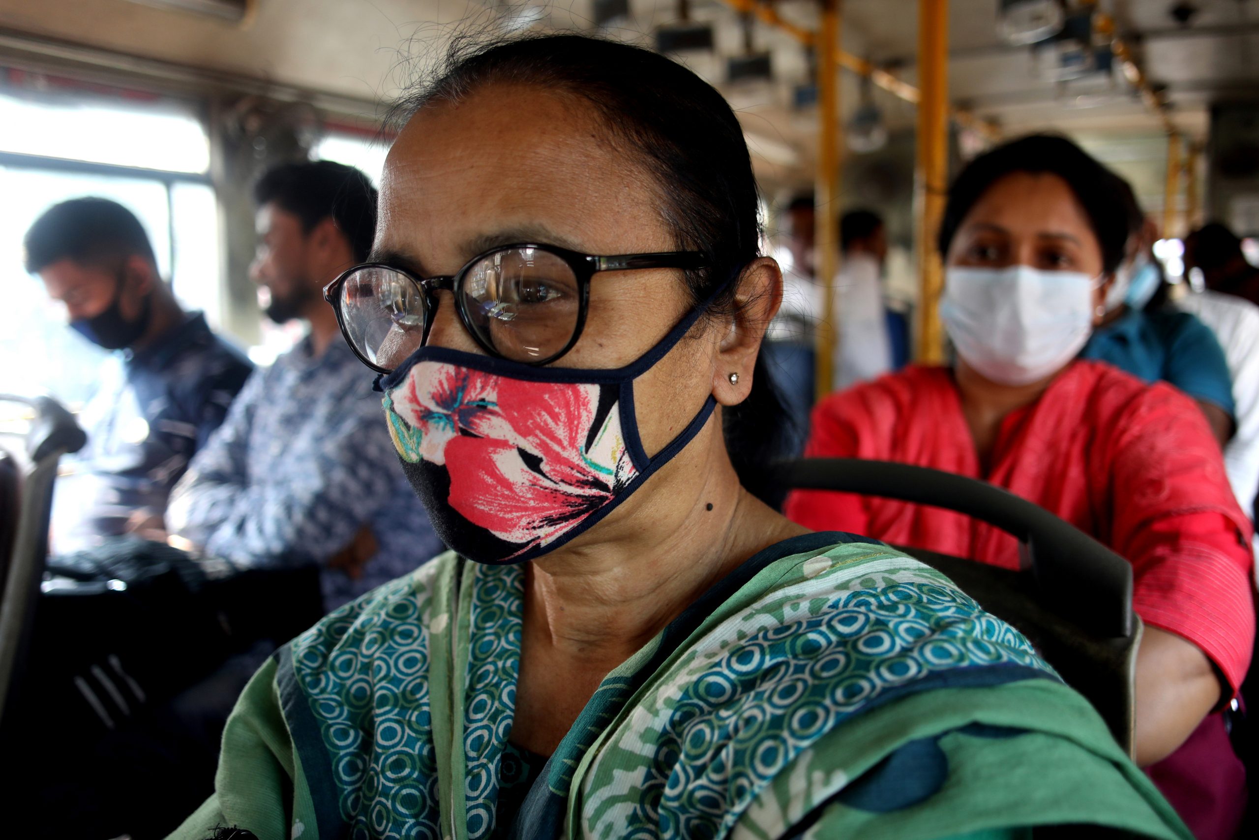 People wearing face masks are seen on a bus in Dhaka.
